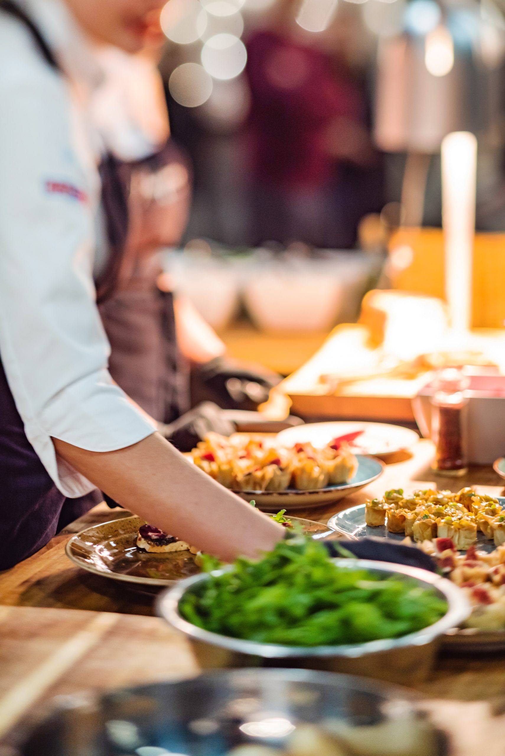 Chef at work in the kitchen, plating food on a wooden counter.